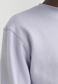 Lavendel pullover sweatshirt met een ronde halslijn, zachte textuur en zichtbare stikdetails op de schouders.