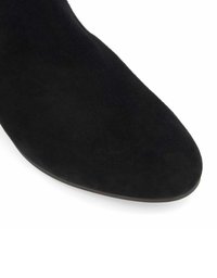 Black suede ankle boot with a pointed toe and a smooth texture. The sole is flat, showcasing a clean design and subtle shaping.