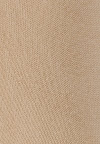 Gebreide stof in een lichte beige kleur met een diagonaal ribpatroon en een zachte textuur, geschikt voor kleding of accessoires.
