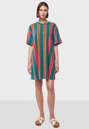 Vestito in maglia con strisce verticali verde, rosa e arancione. Maniche corte, vestibilità ampia e scollatura rotonda. Indossato con sandali beige e gialli.
