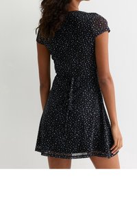 Černé šaty s květinovým vzorem malých modrých květin, krátkými rukávy, staženým pasem a rozšířenou sukní. Měkká, lehká látka.