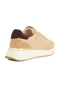 Baskets beiges en suède et matériaux lisses, avec un contre-pied marron, des lacets blancs et une semelle contrastante blanche et beige.