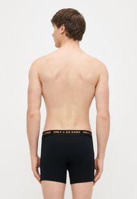 Černé boxerky z bavlny s elastickým pasem, na kterém je nápis "ONLY & SONS" v oranžové barvě. Jednoduchý design s přiléhavým střihem.