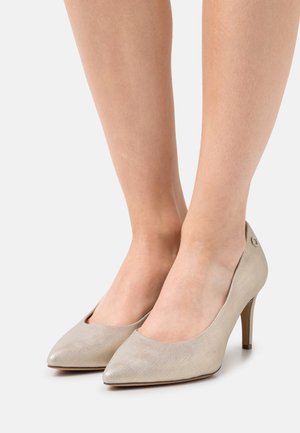 Chaussures à talons aiguilles beiges avec une surface texturée, un design à bout pointu et un petit logo sur le talon.