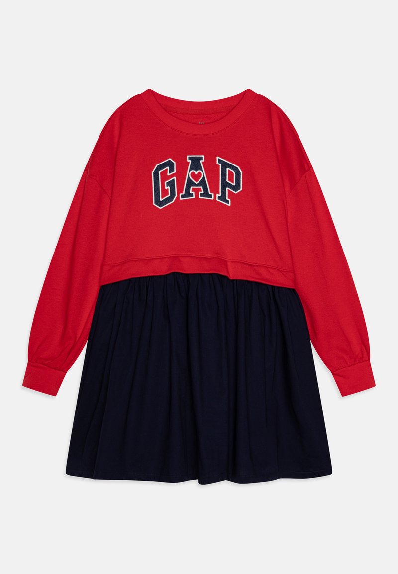 Tricou roșu cu mânecă lungă și fustă bleumarin, având detaliu cu logo-ul "GAP" sub forma unui inima. Material din bumbac, croială lejera, talie elastică.