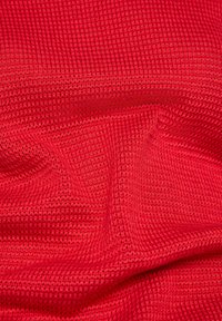 Roter strukturierter Stoff mit einem Rautenmuster, der eine weiche, gewebte Textur aufweist. Das Material wirkt leicht und flexibel, geeignet für Kleidung oder Bastelprojekte.