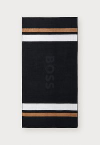 Asciugamano nero con strisce orizzontali bianche e dorate, con il logo "BOSS" subtly impresso al centro. Texture morbida e forma rettangolare.