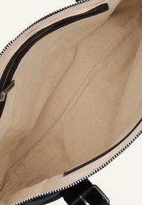 Zwarte rits tote bag interieur met beige canvas voering, met een zijrits zak en gladde, onbewerkte oppervlakken.