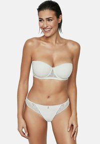 Soutien-gorge blanc sans bretelles avec des bordures en dentelle et des bords festonnés, associé à un string en dentelle assorti avec un petit accent doré. Texture lisse.