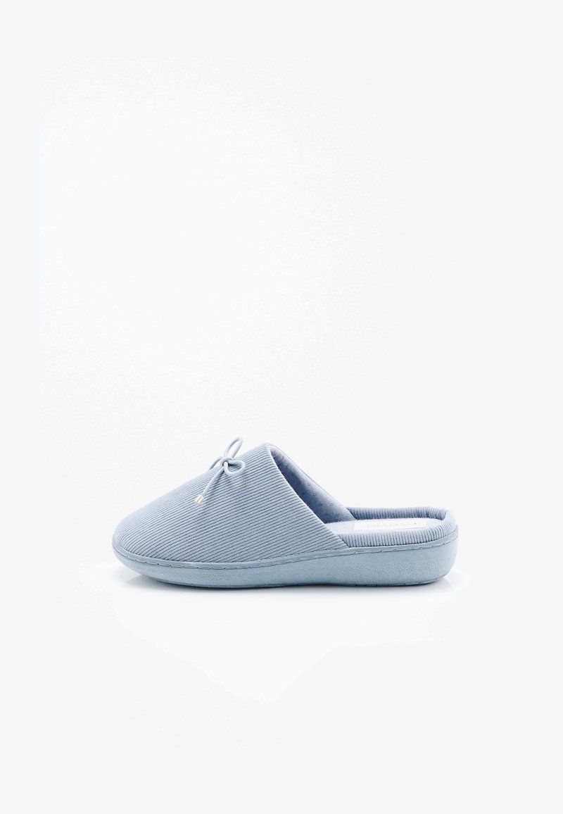 Chausson bleu clair à enfiler avec tissu côtelé, petit nœud sur le dessus et semelle rembourrée, présenté en vue latérale sur fond blanc.