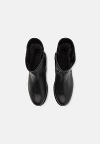 Paire de bottines en cuir noir avec doublure intérieure en polaire, vue de dessus sur un fond blanc uni.