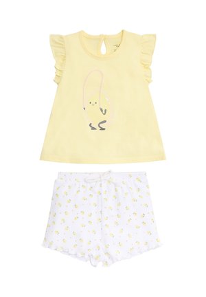 Camiseta amarilla para niño pequeño con mangas con volantes y gráfico de huevo saltarín, combinada con pantalones cortos blancos con un pequeño patrón de pollitos amarillos.