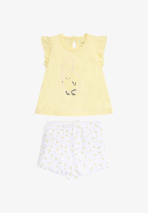 Camiseta amarilla para niño pequeño con mangas con volantes y gráfico de huevo saltarín, combinada con pantalones cortos blancos con un pequeño patrón de pollitos amarillos.