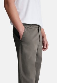 Chino grigi leggeri con un design a gamba dritta, dotati di tasche laterali, zip e una trama di tessuto liscia.