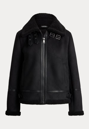 Mustat tekosuede-takit, joissa on shearling-kaulus, vetoketjukiinnitys, sivutaskut sekä nahkakiinnitykset helman ja hihansuiden ympärillä. Ominaisuuksiin kuuluu säätöremmit olkapäillä.