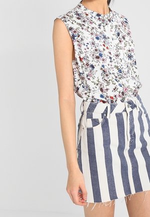 Bloemen mouwloze blouse met een hoge halslijn, gecombineerd met een hoge taille spijkerrok met blauwe en witte verticale strepen.