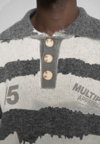 Pulover tricotat cu dungi gri și albe, prezentând un guler colier, o închidere cu patru nasturi și numărul '5' tipărit pe partea din față.