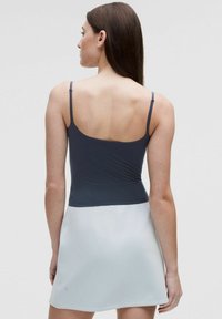 Grå tanktopp med tunna spännen övergår till en ljusgrå kjol. Slät textur, figurnära byst och kort design.
