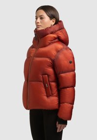 Czerwona kurtka typu puchowa z błyszczącym, pikowanym wykończeniem, wysokim kołnierzem, regulowanym kapturem, kieszeniami na zamek i detalem z logo na rękawie.