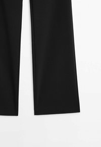 Pantalon noir à jambes larges avec une texture de tissu lisse, présenté de la mi-cuisse vers le bas sur un fond blanc.