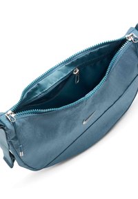 Τσαντάκι crossbody σε τιρκουάζ νάιλον με φερμουάρ στην κορυφή και ασημί αξεσουάρ, που διαθέτει ένα μικρό λογότυπο Nike στο πλάι. Λείο υλικό, συμπαγής σχεδίαση.