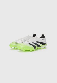 Soccer cleats with a white upper featuring black stripes and grip texture, vibrant green sole, and conical studs for traction.