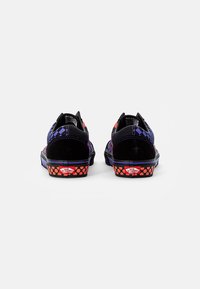 Sneakers din suede negru și pânză verificată mov, cu talpă neagră și accente punctate roșu-portocalie pe călcâi. Logo-ul Vans este vizibil.