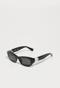 Schwarze rechteckige Sonnenbrille mit dunklen Gläsern, die an jedem Bügel mit einem rhombusförmigen Kristallakzent und einem glänzenden Rahmen versehen ist.