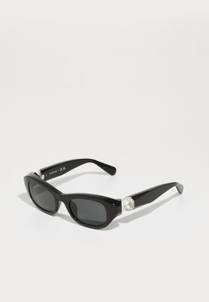 Schwarze rechteckige Sonnenbrille mit dunklen Gläsern, die an jedem Bügel mit einem rhombusförmigen Kristallakzent und einem glänzenden Rahmen versehen ist.