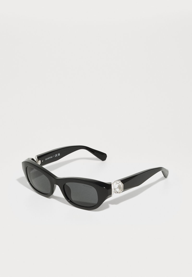 Schwarze rechteckige Sonnenbrille mit dunklen Gläsern, die an jedem Bügel mit einem rhombusförmigen Kristallakzent und einem glänzenden Rahmen versehen ist.