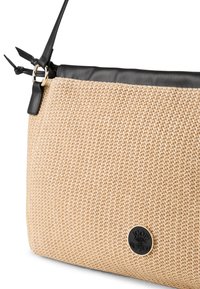 Beige vävd tyghandväska med svart läderkant, med en guldfärgad cirkulär logotypdetalj och en avtagbar rem. Strukturerad yta.