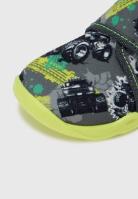 Szürke szövet cipő fekete monster truck mintával és zöld részletekkel. A talp élénk lime zöld színű, mintás felülettel.