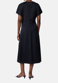 Długa, ciemnoniebieska sukienka z krótkimi rękawami, zamkiem błyskawicznym z tyłu i gładkiego, matowego materiału. Do kolan z rozkloszowanym krojem spódnicy.