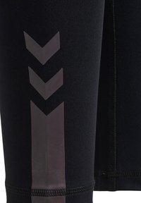 Svarta träningsleggings med en slät yta, featuring en glänsande grå chevronmönster längs sidan och en robust söm i nederkant.