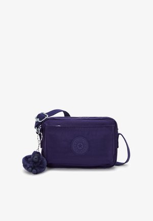 Bolso cruzado rectangular morado con correa ajustable, bolsillo frontal con cremallera y un pequeño llavero de gorila de peluche adjunto.