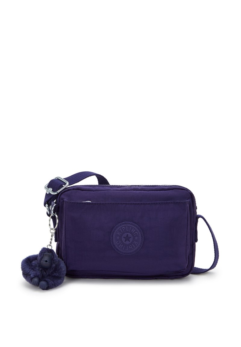 Fioletowa prostokątna torba na ramię z regulowanym paskiem, przednia kieszeń na zamek oraz mały pluszowy breloczek w kształcie goryla przymocowany.