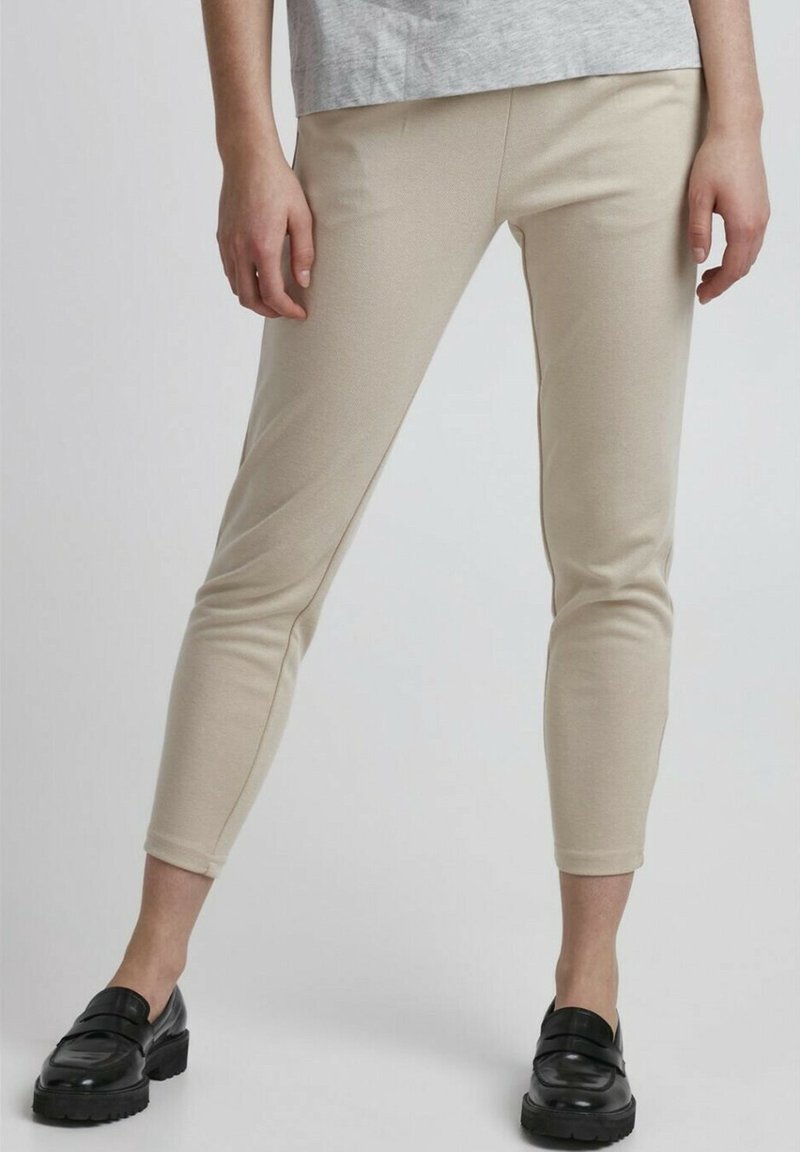Beige skinny trousers met een zachte textuur, met een taps toelopend ontwerp en enkellengte. G gedragen met zwarte instappers.