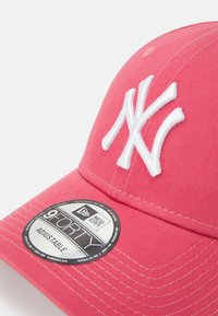 Vaaleanpunainen baseball-lippis, jossa on brodattu valkoinen logo, säädettävä hihna ja jämäkkä muotoilu. Varustettu käyrällä lippaalla ja merkkitagilla.