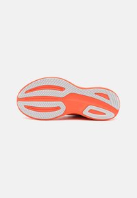 Hardloopschoen zool met een fel oranje gedeelte en witte rubber. Kenmerkt groeven en textuurpatronen voor grip. Logo aanwezig.