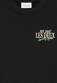 Black crewneck sweatshirt with embroidered logos in white and light green. Material appears soft with a smooth texture. Tag visible at the neckline.