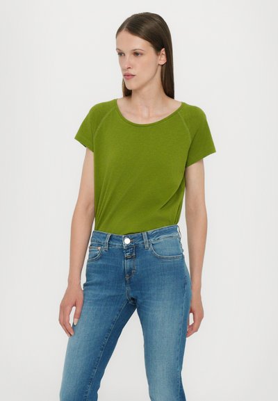 Grønn topp med korte ermer i et lett stoff med rund hals, kombinert med blå denimjeans med en klassisk fem-lomme design.