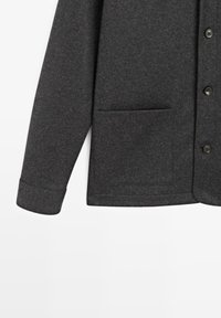 Szara kurtka zapinana na guziki z teksturowanej tkaniny. Posiada kieszeń na piersi, długie rękawy oraz guziki z przodu.