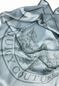 Hedvábný modrý šátek s šedým reliéfním vzorem zvířat a ozdobných motivů, okrajovaný tmavším modrým lemem.