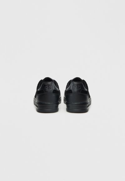 Μαύρα αθλητικά παπούτσια με λείο δέρμα στην επάνω επιφάνεια, υφασμάτινες υφές και λογότυπο στη φτέρνα, σχεδιασμένα με χαμηλό προφίλ.