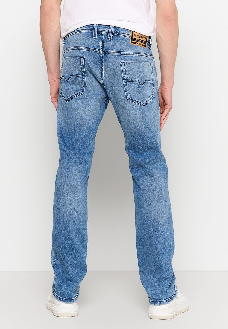 Jean en denim bleu clair avec une coupe droite, deux poches arrière et une étiquette en cuir de marque au-dessus de la poche droite.