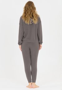 Grau melierter Pullover mit Kapuze und passender enganliegender Hose. Weiche Textur, lockere Passform und elastische Bündchen. Keine sichtbaren Muster oder Hardware-Akzente.