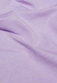 Tissu coton lavande avec une surface lisse et légèrement texturée, présentant de douces plis et un subtil éclat. Idéal pour les vêtements ou la literie.