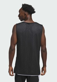 Sort mesh ærmeløs tank top med en løs pasform, der har et enkelt design og en rund halsudskæring. Bagsiden viser et struktureret stofdetalje.