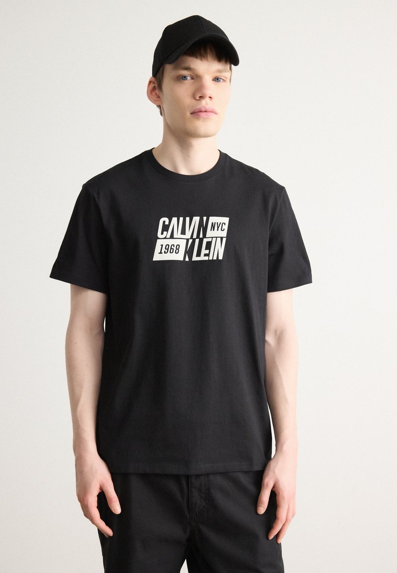 Fekete pamut póló, fehér grafikával, amelyen vastag betűkkel szerepel a "CALVIN 1968 NYC KLEIN" felirat. Kerek nyakkivágás, rövid ujjak.
