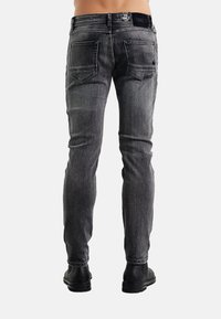 Jeans skinny in denim grigio scuro con finitura testurizzata. Presentano una vita standard, cinque tasche e cuciture a contrasto sulle cuciture.